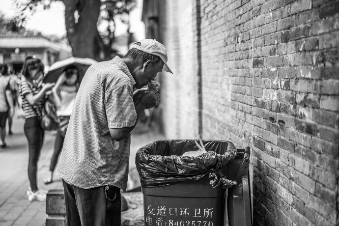 a man standing next to a trash can